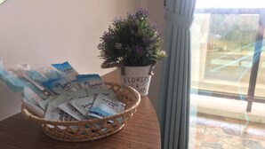 Una cesta de mimbre llena de paquetes de organizador de ducha sobre una mesa de madera, junto a una maceta con una etiqueta que dice 'FLOWERS & GARDEN'.