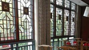A dining area with wooden tables and chairs, some with red napkins. - Aode Hotel (Hangzhou)
