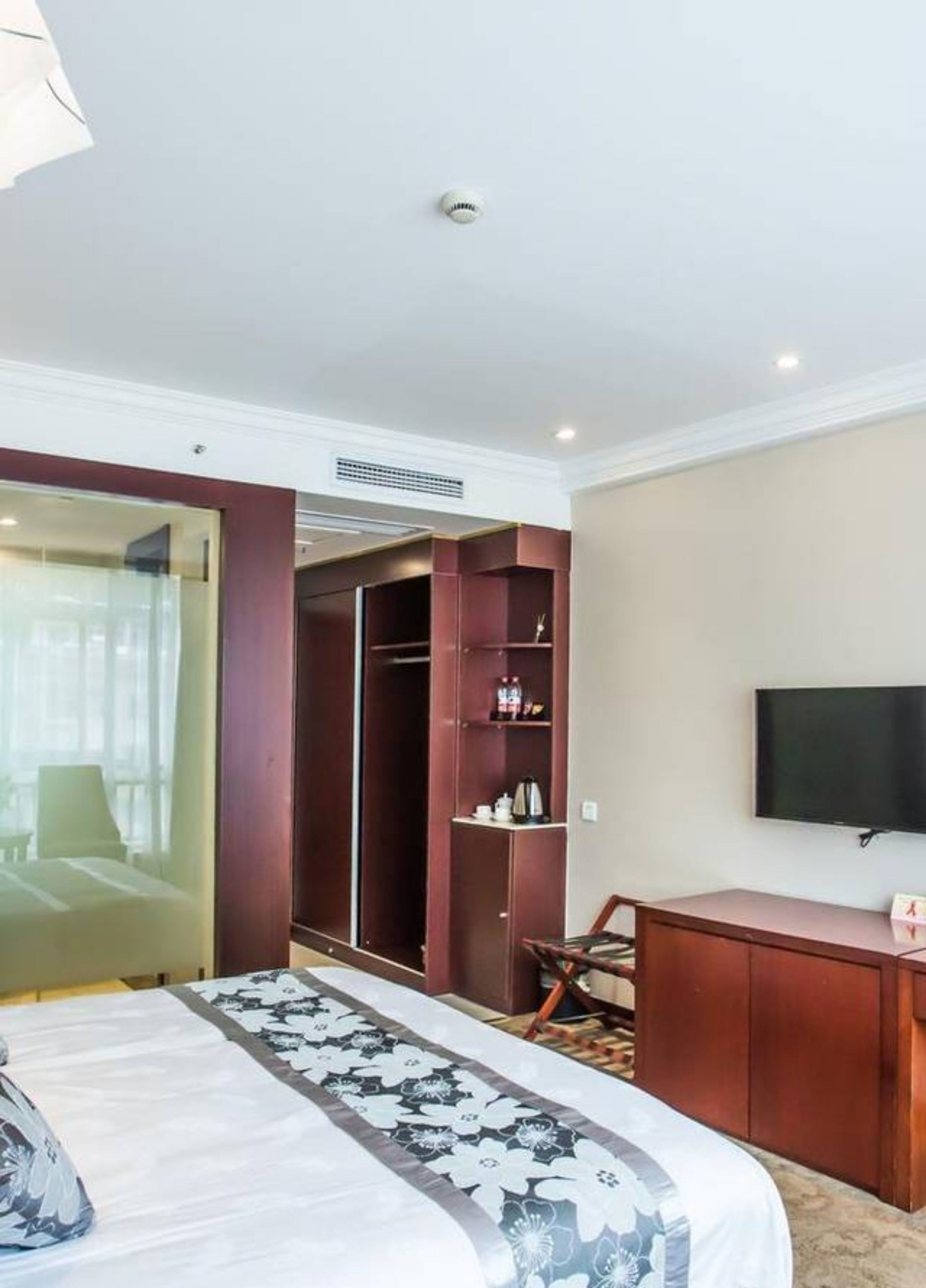 A hotel room with a bed, a wardrobe, a desk, and a television.