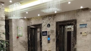 A lobby with marble flooring, a chandelier, and two elevators. - Aode Hotel (Hangzhou)