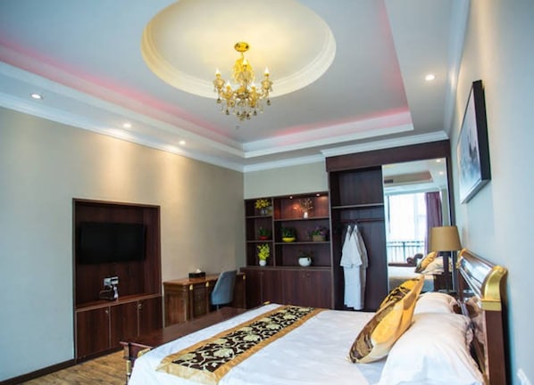 Una habitación de hotel con una cama grande, televisor, escritorio y armario.