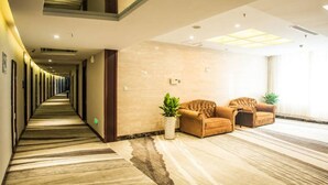 A hotel lobby with a long corridor, a seating area with sofas, and a large potted plant. - Aode Hotel (Hangzhou)