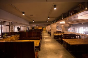 Un restaurante con cabinas y mesas de madera, un revestimiento de azulejos y una barra larga.