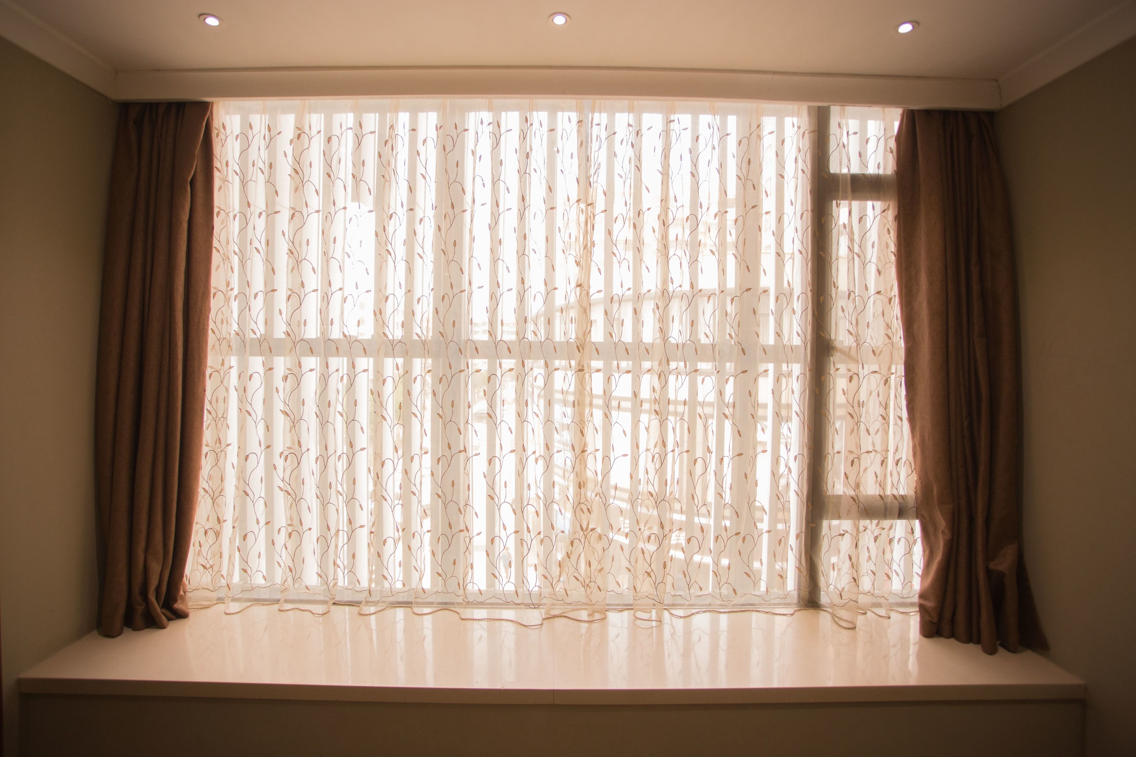 Una ventana con cortinas traslúcidas y vista al exterior.