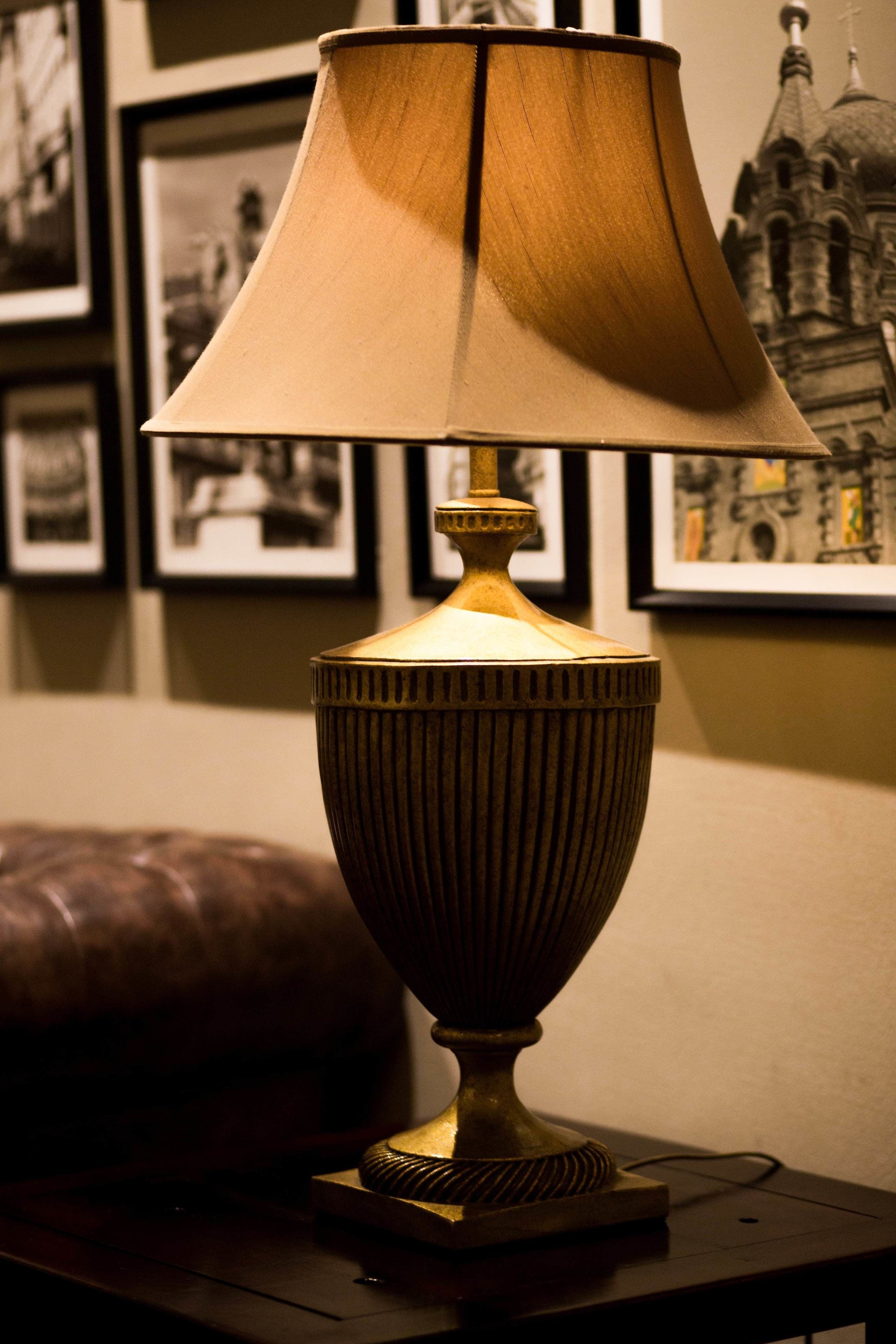 A table lamp with a ribbed base and a conical shade, placed on a dark wooden table.