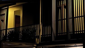 A building with a balcony and vertical blinds, under a night sky with a visible moon. - SUNKISS pool.bed.cafe (Bangkok)