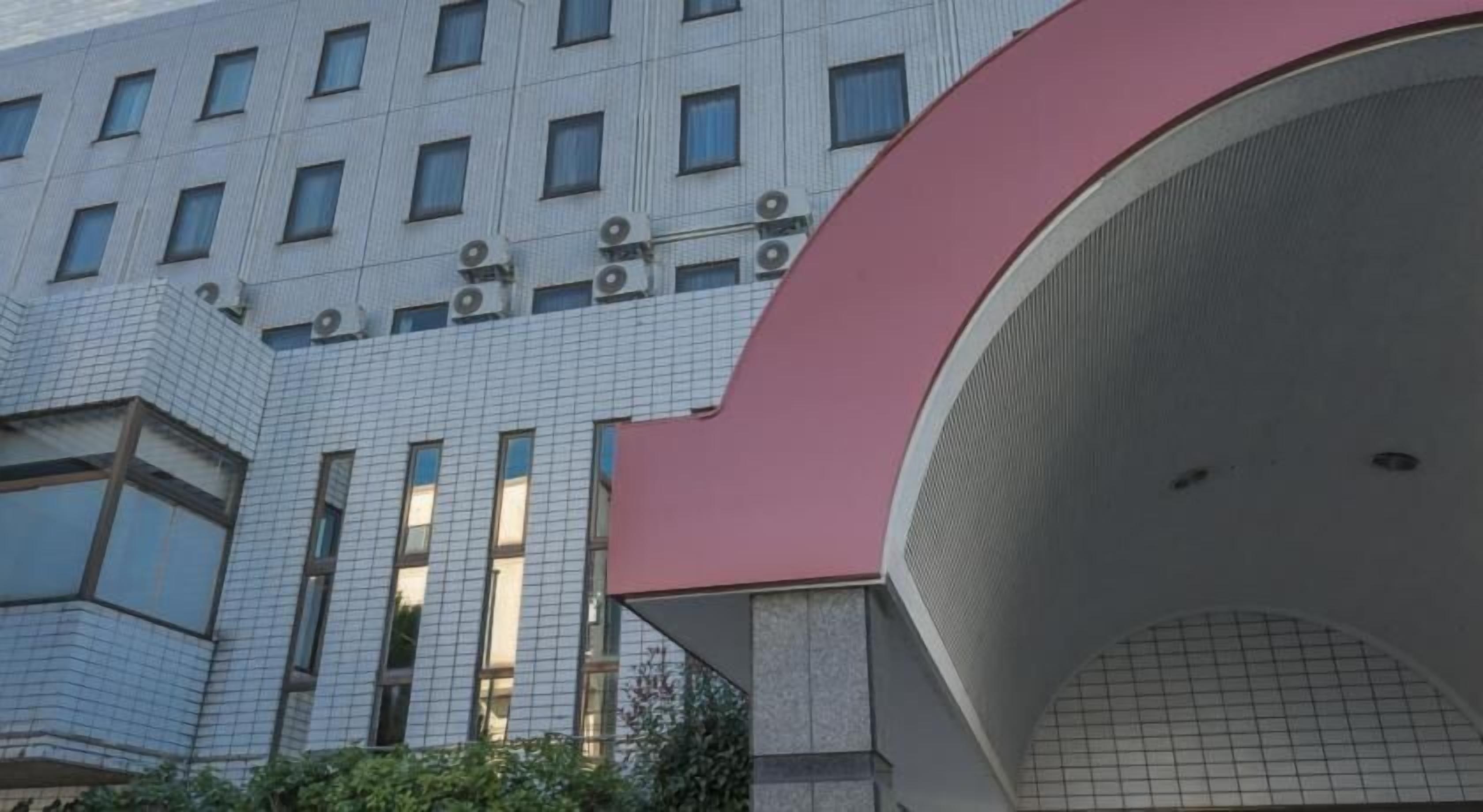 A modern building with a grid-patterned facade, large windows, and a prominent red arch structure.
