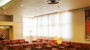 Un hall de hotel con sofás de cuero, una mesa de centro y un gran ventanal con cortinas.