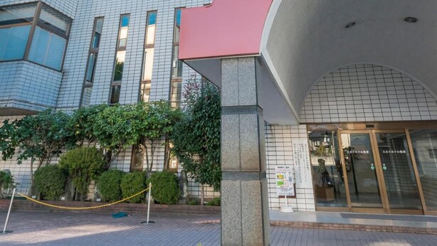 Un hotel con fachada moderna, una entrada destacada con un alero curvo y cielo despejado.