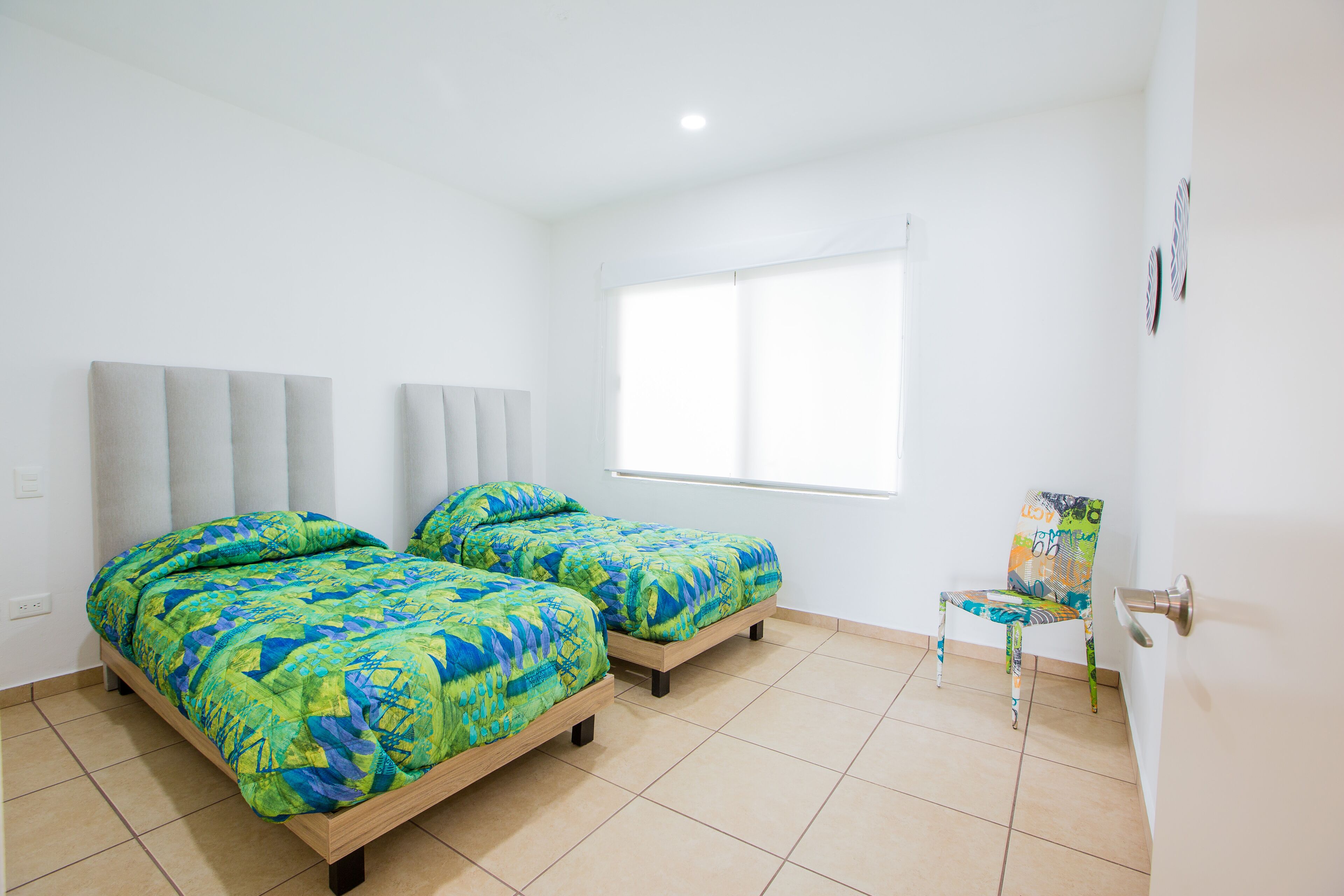 A room with two beds, a chair, and a window.