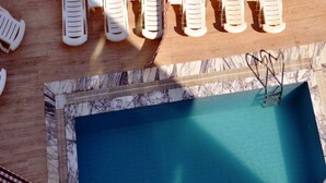 A poolside area with several white lounge chairs arranged in rows. - Almena City Hotel (Marmaris)