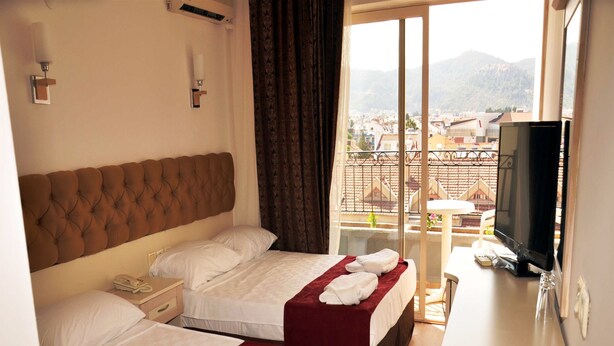 A hotel room with two beds, a TV, and a balcony with a city view. - Almena City Hotel (Marmaris)