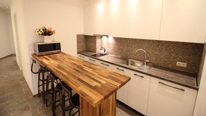 Una cocina moderna con una isla de madera, taburetes de bar, un microondas y un lavamanos.