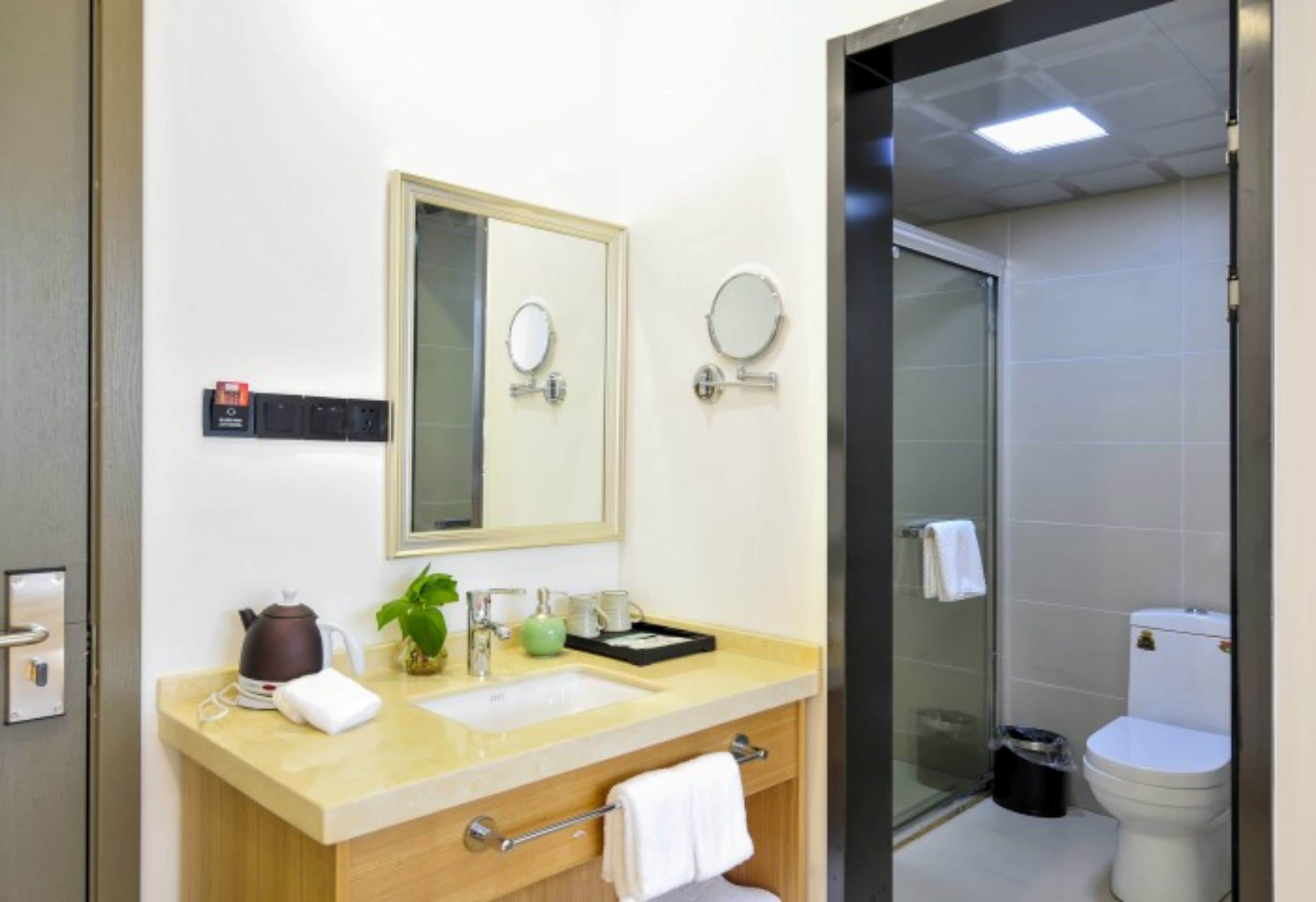 A modern bathroom with a sink, mirror, and toilet.