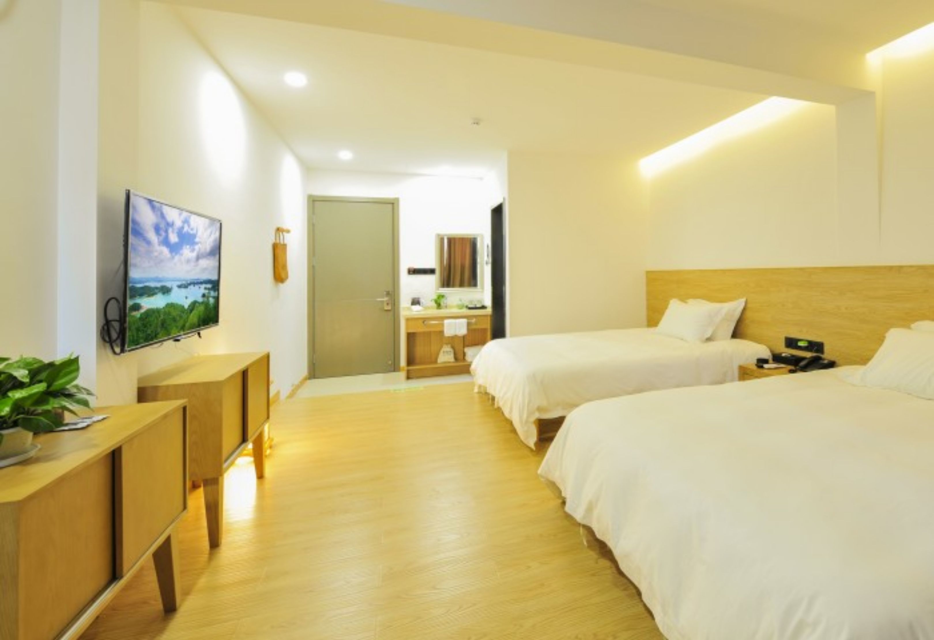 Habitación de hotel con dos camas, un escritorio de madera, televisión y vistas a un paisaje.