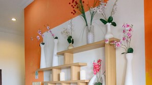 A modern reception area with a wooden shelving unit displaying various vases and decorative items. -  Homestay Sawitsari dekat Pakuwon Mall dan UGM by Simply Homy (Depok)