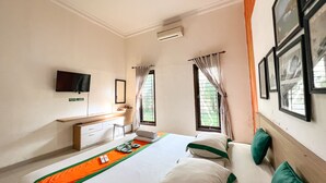 A hotel room with a bed, a TV, a desk, and a window with curtains. -  Homestay Sawitsari dekat Pakuwon Mall dan UGM by Simply Homy (Depok)