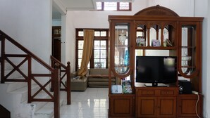 A living room with a wooden TV stand, a television, and a staircase. - Simply Homy Guest House Unit Kaliurang 2 (Ngaglik)