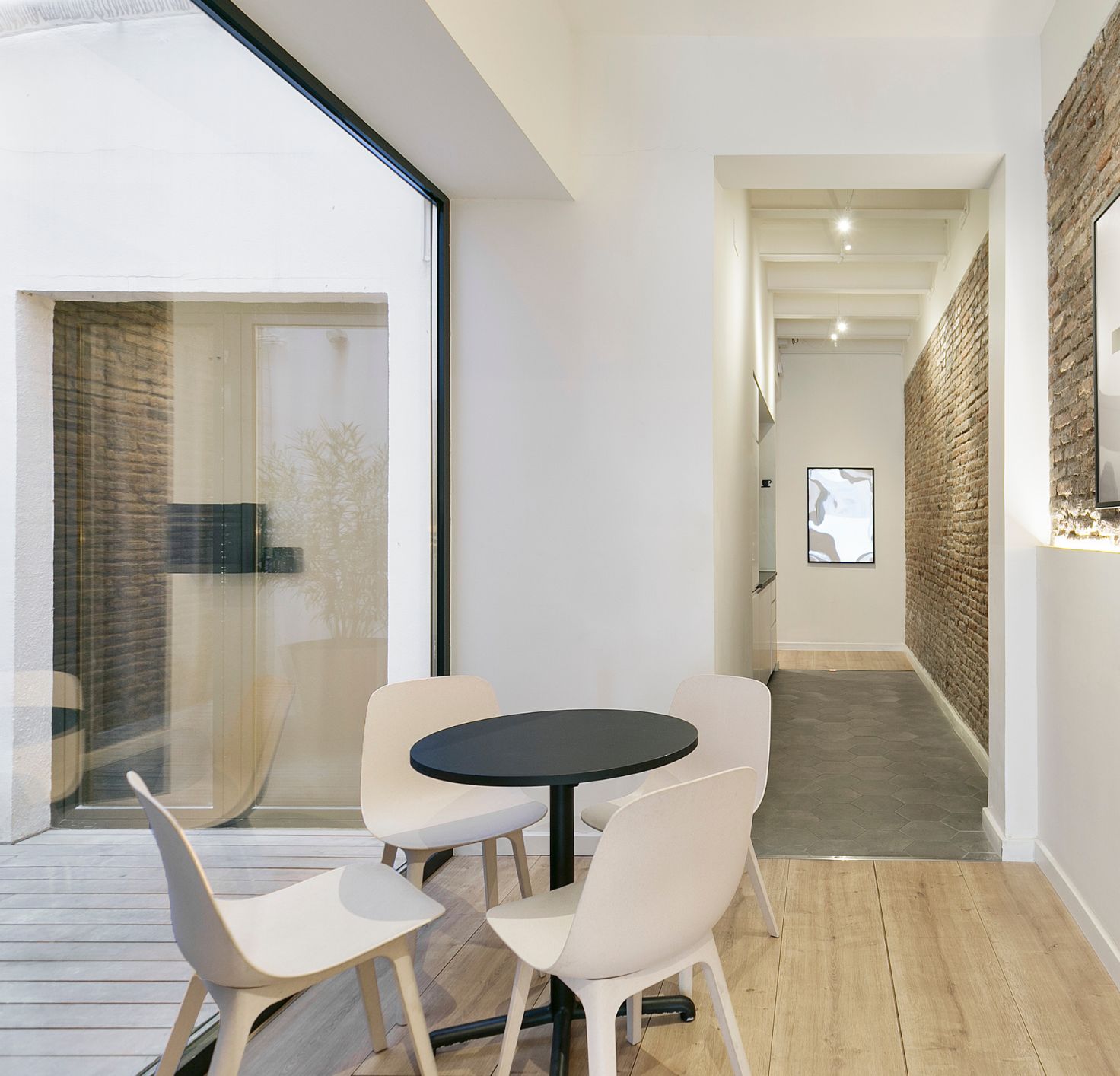 Un intérieur moderne avec une table ronde et des chaises, un mur décoratif en briques et un panneau indiquant « Espace partagé ».