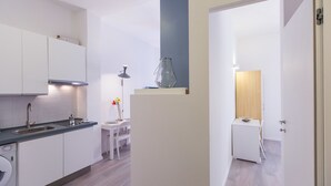 Une cuisine moderne équipée d’un lave-vaisselle intégré, un coin repas avec une table et des chaises, et un petit espace détente avec une lampe.