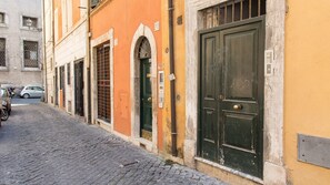 A cobblestone street with buildings featuring arched windows and doors, numbered signs, and a metal mail slot. - Rental In Rome Beato Angelico Second Apartment (Rome)