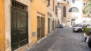 Une ruelle étroite pavée, bordée de bâtiments historiques, avec une porte noire et des fenêtres grillagées sur le côté gauche.