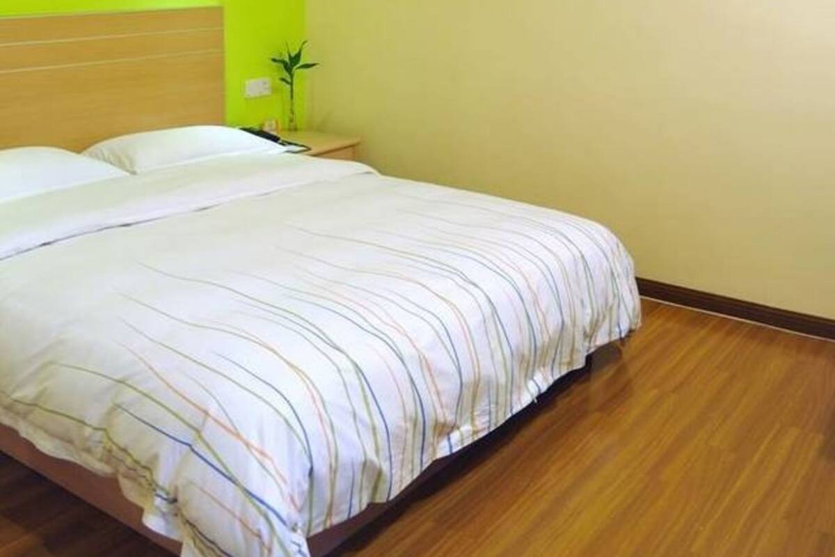 Ein Hotelzimmer mit einem großen Bett, einem Nachttisch mit Lampe und einer Wand mit einem rot-weißen abstrakten Gemälde.