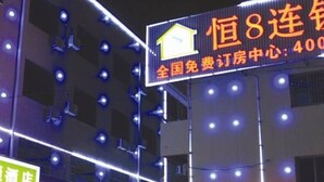 A building with multiple floors, illuminated by blue lights. There is a prominent sign with Chinese characters and a house icon, indicating a hotel or accommodation center. - Heng 8 Hotel Hangzhou Xiaoshan Airport (Hangzhou)