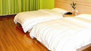 A hotel room with two beds, green curtains, a wooden floor, and a small plant on the nightstand. - Heng 8 Hotel Hangzhou Xiaoshan Airport (Hangzhou)