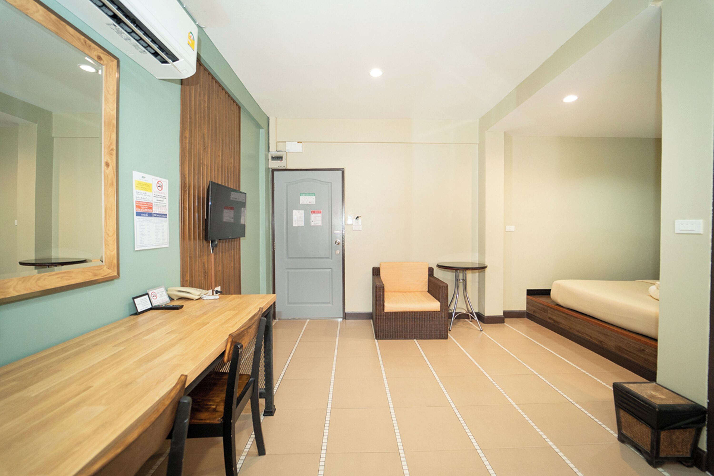 A hotel room with a wooden desk, a chair, a bed, and a television.