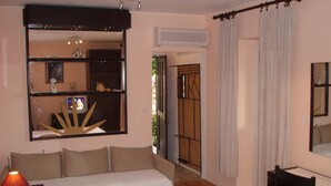 A cozy room with a sofa, a chair, a desk, and a large mirror. - Karla Apartments (Dubrovnik)