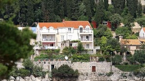 A coastal residential area with stone buildings, some with balconies, and dense greenery. - Karla Apartments (Dubrovnik)