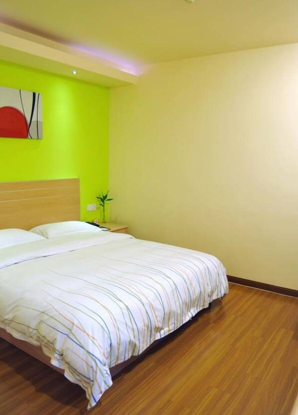 A hotel room with a large bed, a wooden floor, a nightstand with a lamp, and a wall with a red and white abstract painting. - Heng 8 Hotel Tonglu South Yingchun Road (Hangzhou)