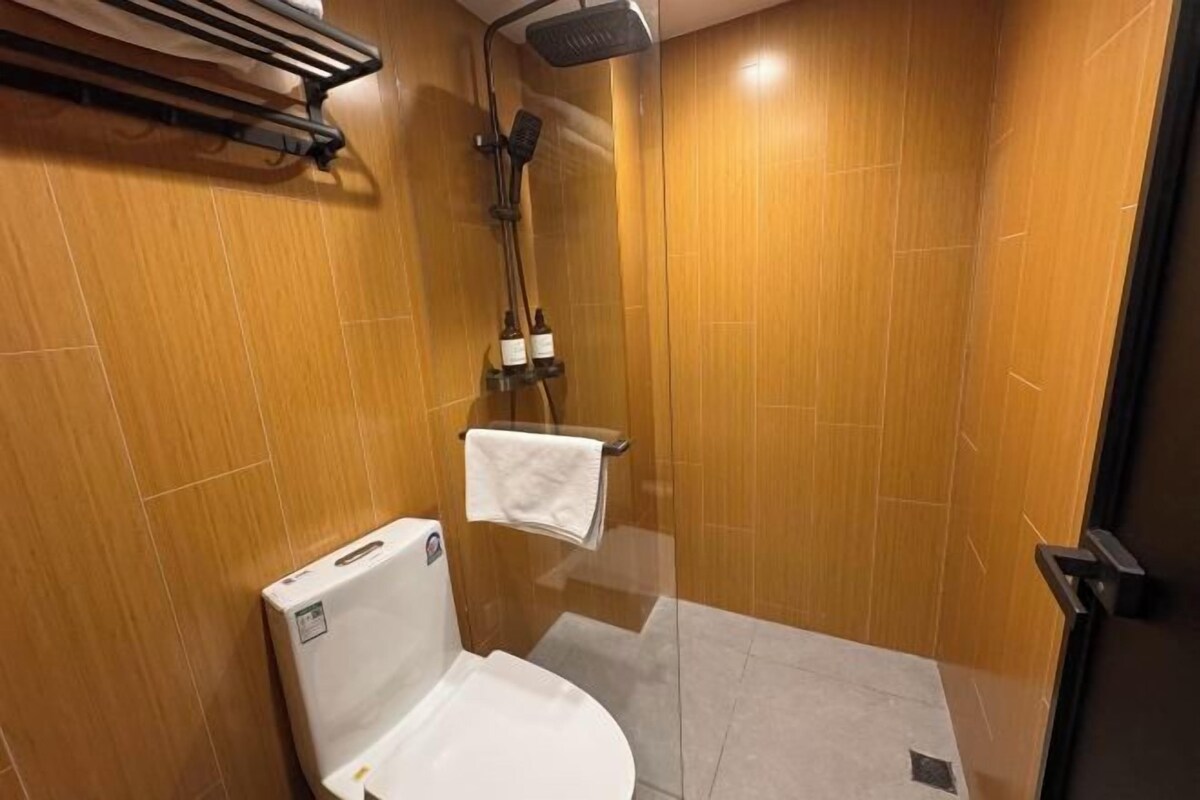 A small, compact bathroom with a shower, toilet, and towel rack.