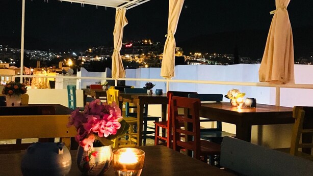 An outdoor dining area with a table set for two, featuring a candle and a vase of flowers. - Halikarnas Pansiyon (Bodrum)