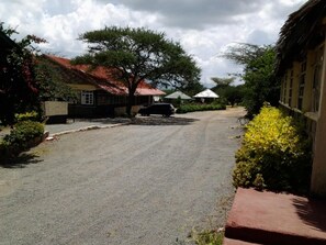 A residential street with houses, a parked car, and a tree. - Kajiado Cultural Resort (Bisil)
