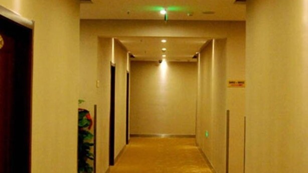 A hotel hallway with carpeted floors, doors on both sides, and a green exit sign. - Wanjing Express Hotel (Hangzhou)