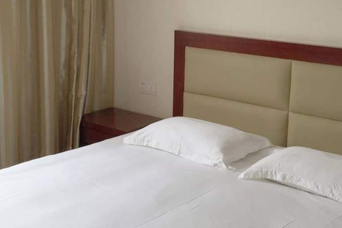 Ein Hotelzimmer mit einem Bett, einem Nachttisch und einem Vorhang.