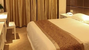 A hotel room with a large bed, a desk with a chair, a bedside table, and a large window with curtains. - Zhongdun Boutique Hotel (Hangzhou)