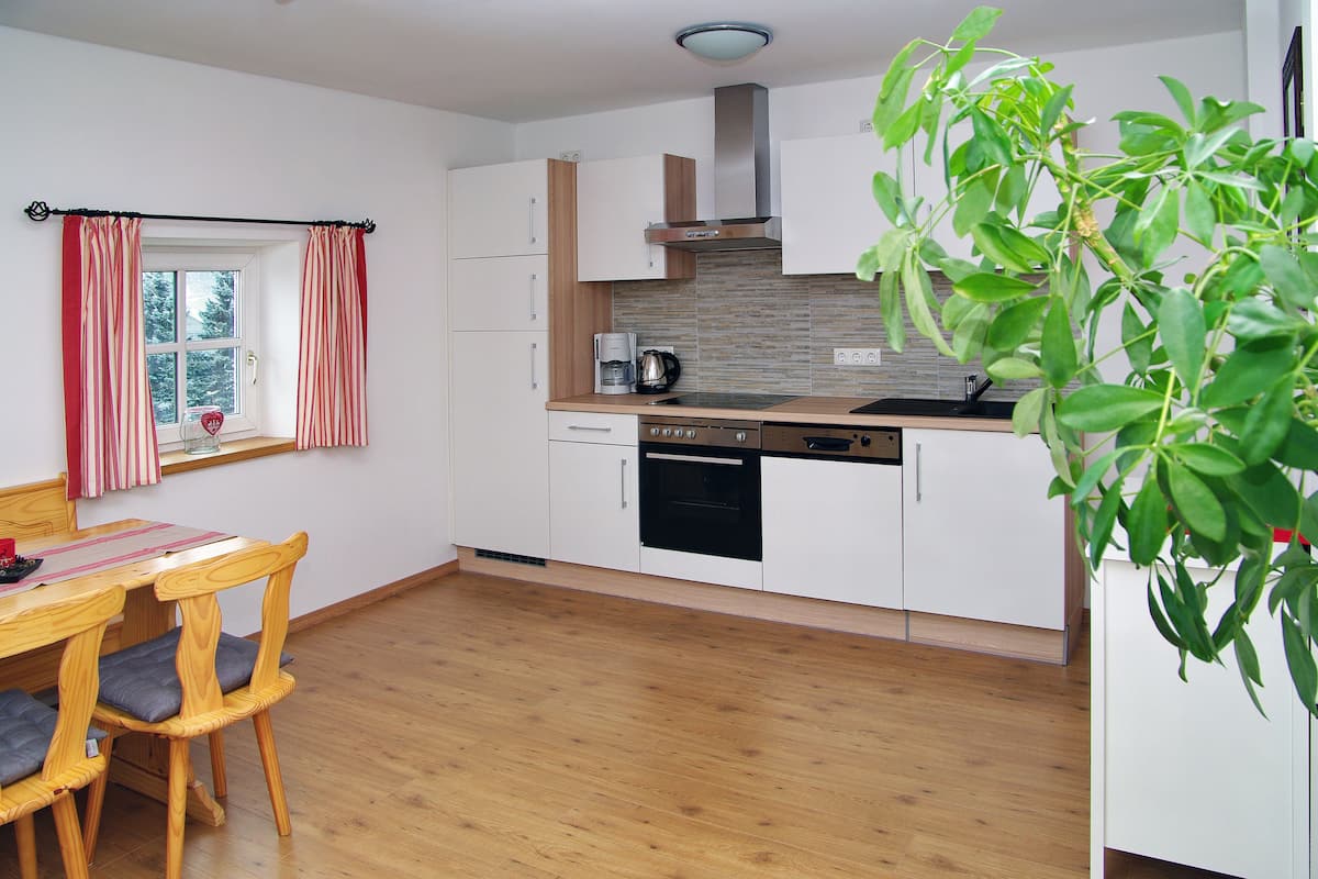 Eine moderne Küche mit weißen Schränken, einer Holz Arbeitsplatte und einem eingebauten Backofen.