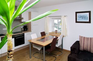 A modern kitchen with a dining area, a black sofa, and a framed picture on the wall. - Haus Auszeit (Rauris)
