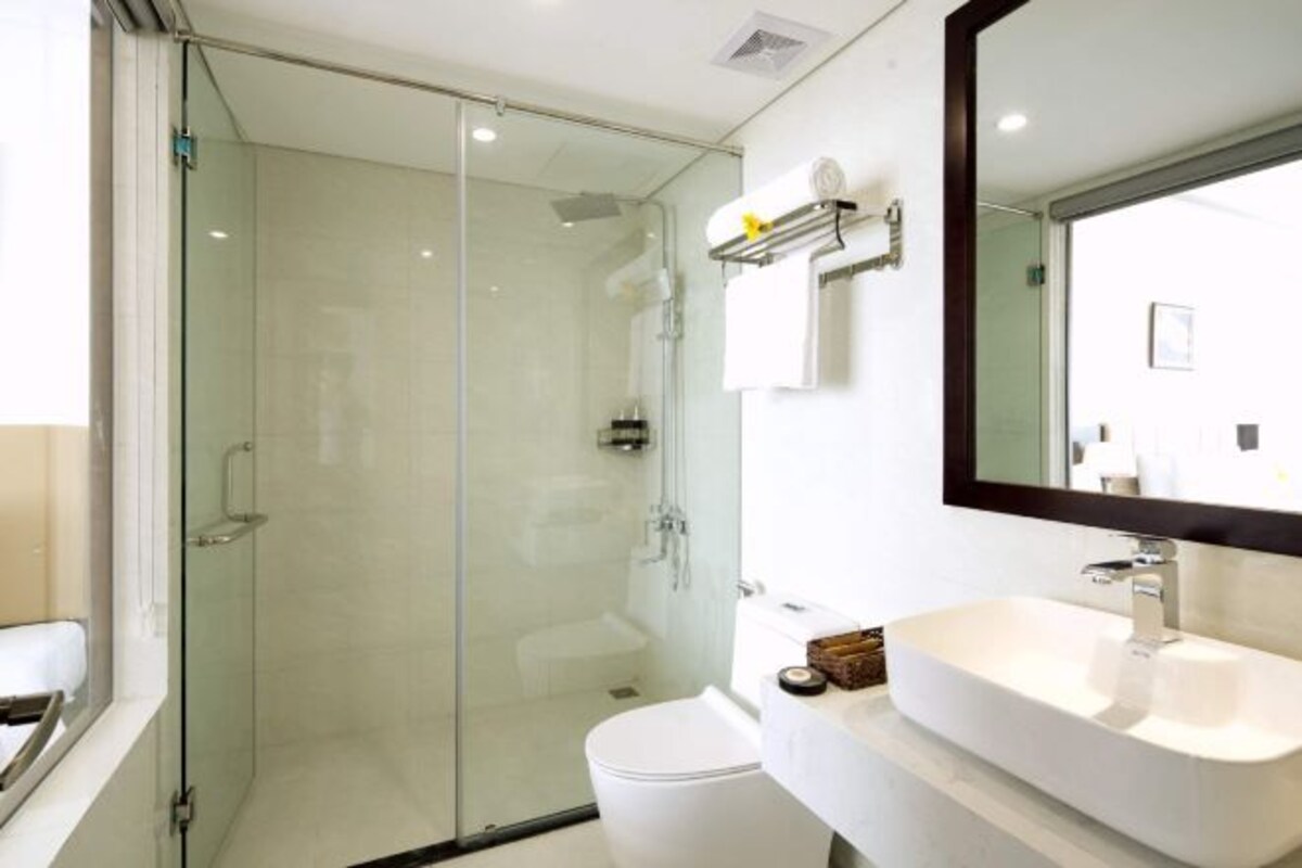A modern bathroom with a glass-enclosed shower, a white sink, and a large mirror.