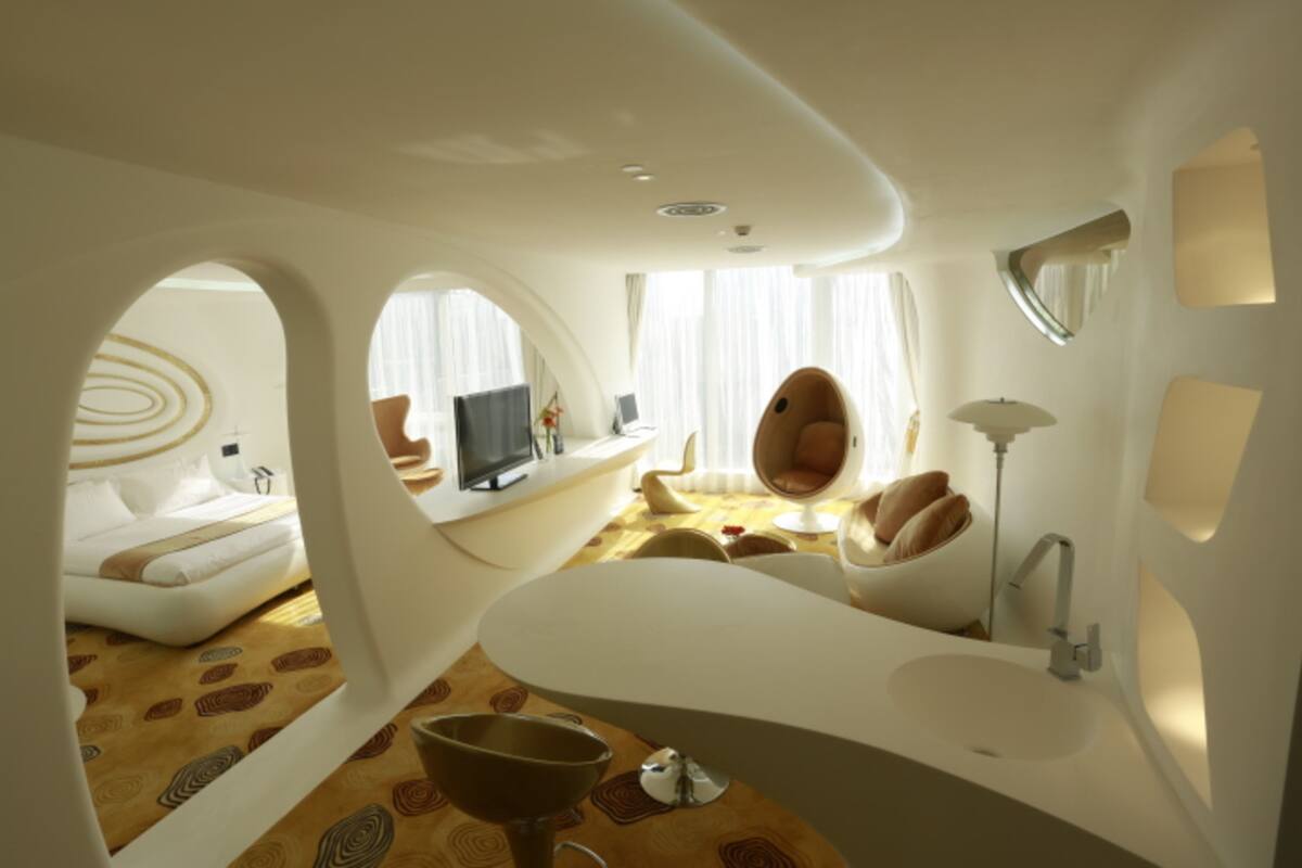Una habitación moderna de diseño único con una bañera blanca curvada, un espejo redondo y un amplio ventanal con cortinas.