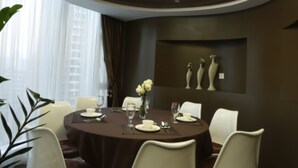 Uma zona de refeições moderna com uma mesa redonda, cadeiras brancas e um candeeiro central.