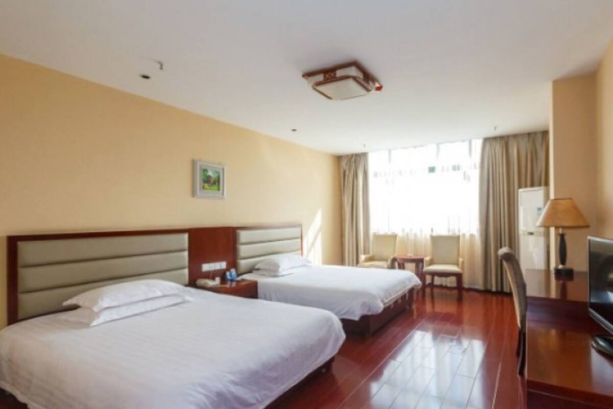 A hotel room with two beds, a TV, a desk, and a chair.