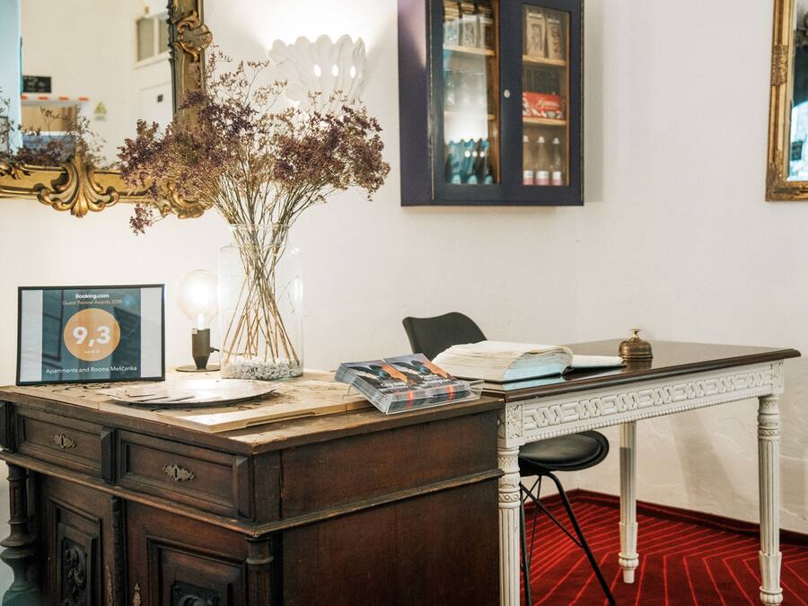 A wooden desk with a vase of dried flowers, a framed certificate, and a lamp.