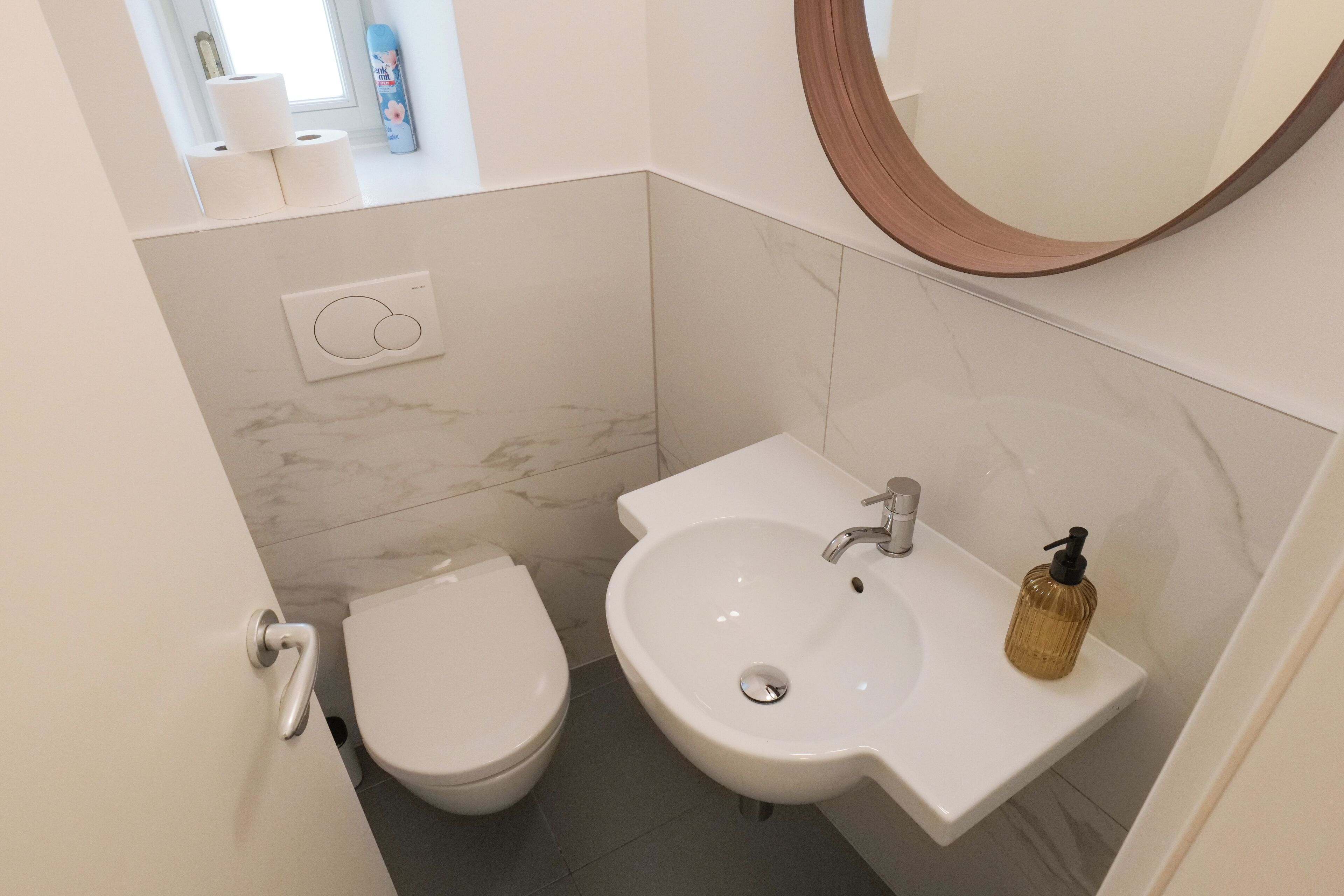 A compact bathroom with a toilet, sink, and a mirror.