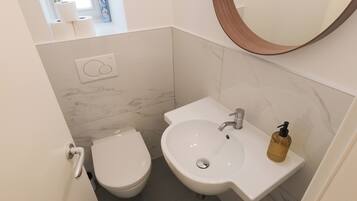A compact bathroom with a toilet, sink, and a mirror.