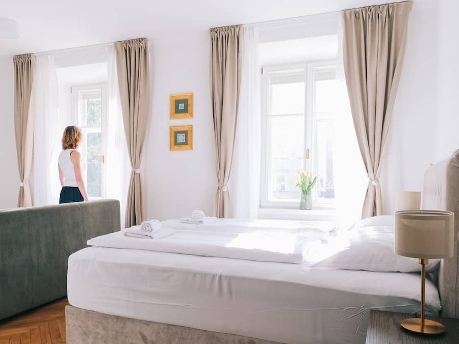 Et hotelværelse med seng, sengetæppe og et vindue med gardiner.