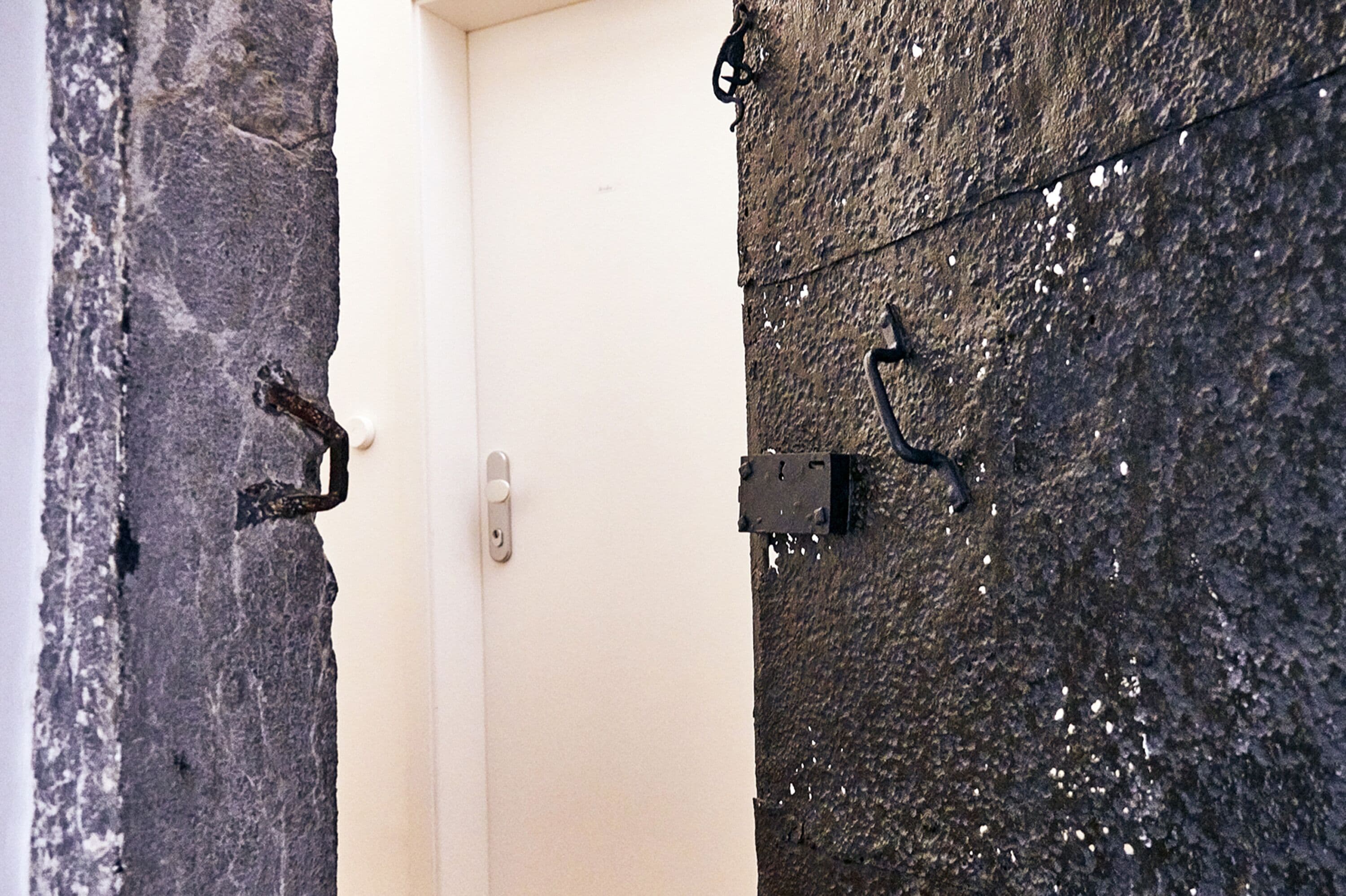 Uma porta com fecho de metal e parede texturizada com acessório metálico.